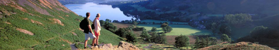 Two walkers looking down onto Ullswater in the Lake District